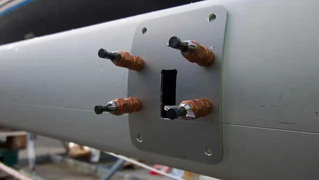 Nærbilde av elektriske gjennomføringer eller koblinger montert på en mast eller bom.